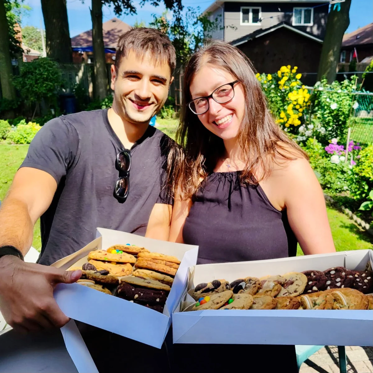 Nefeli and Peter holding boxes of fresh-baked cookies
